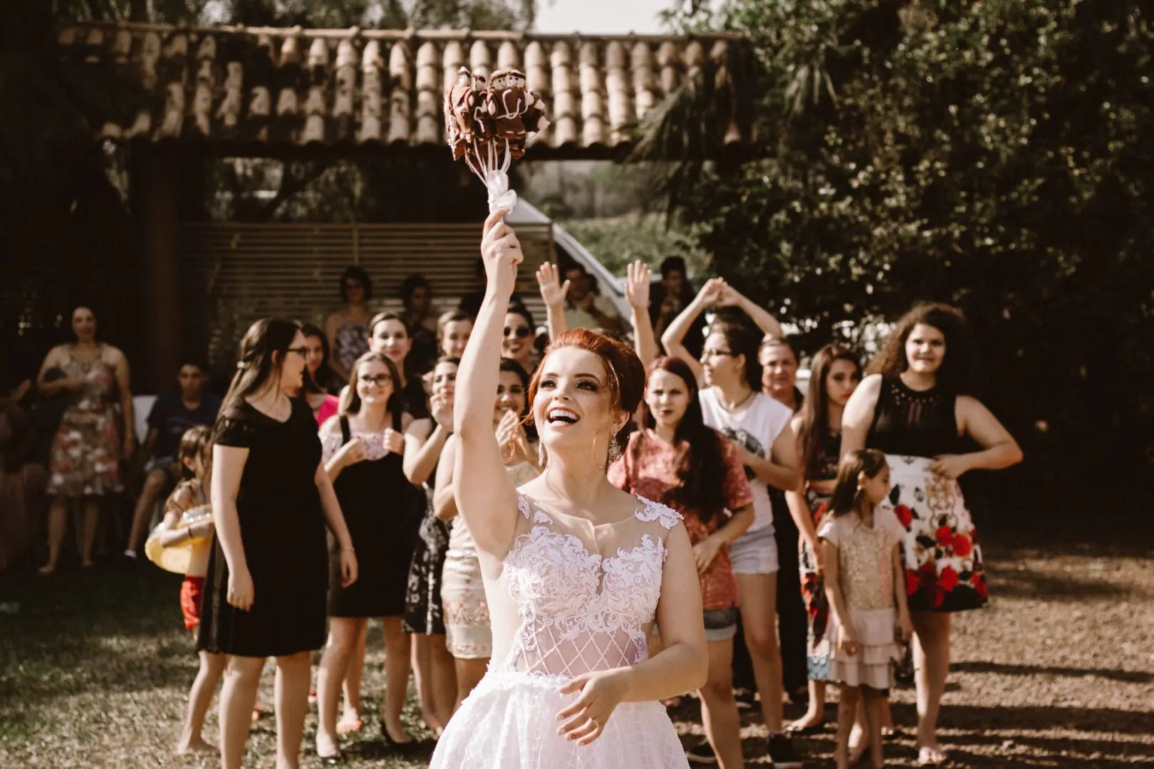 A woman in white dress holding up a bouquet of flowers.