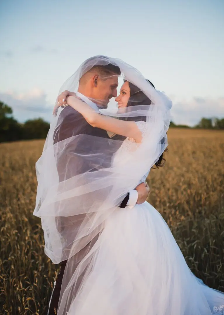 A man and woman embracing in the middle of a field.