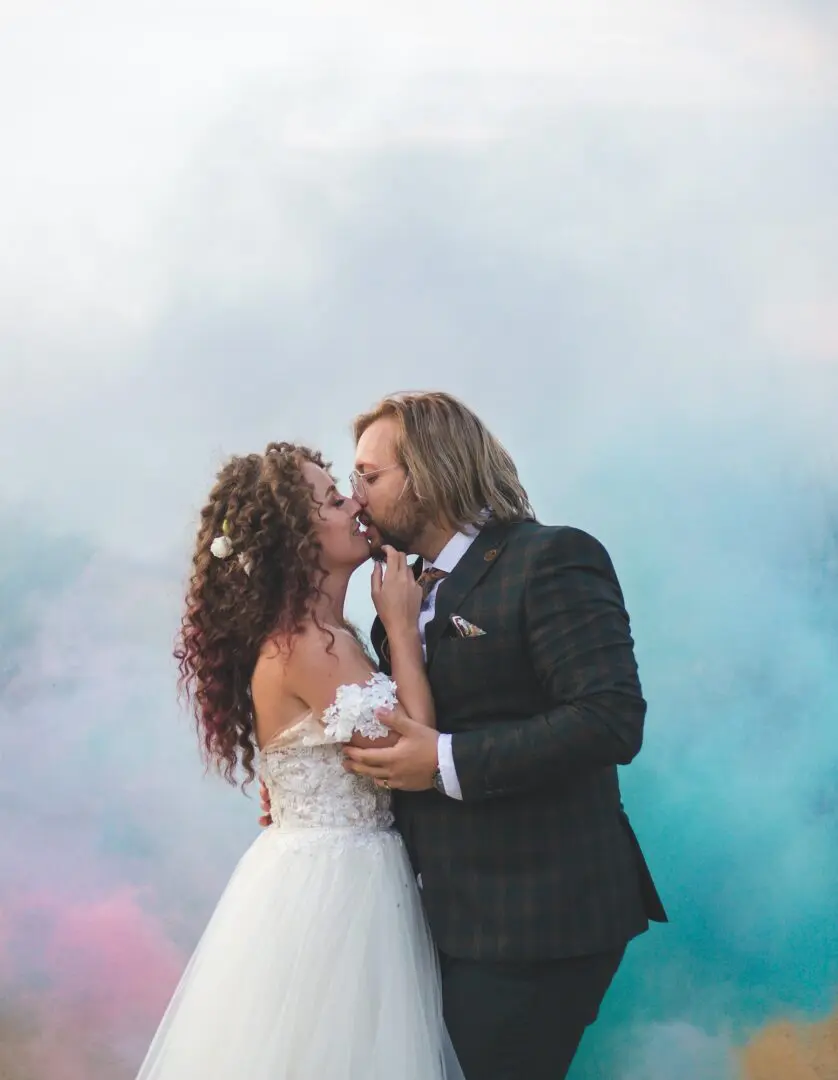 A man and woman kissing in front of a blue sky.