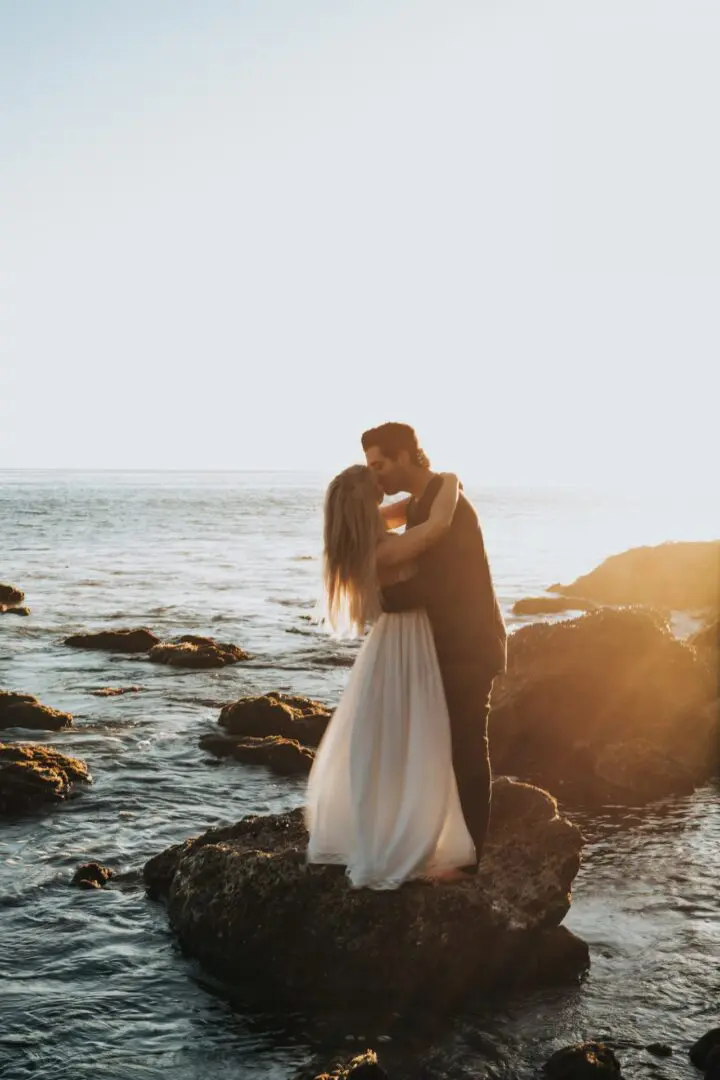 A man and woman kissing on the beach.