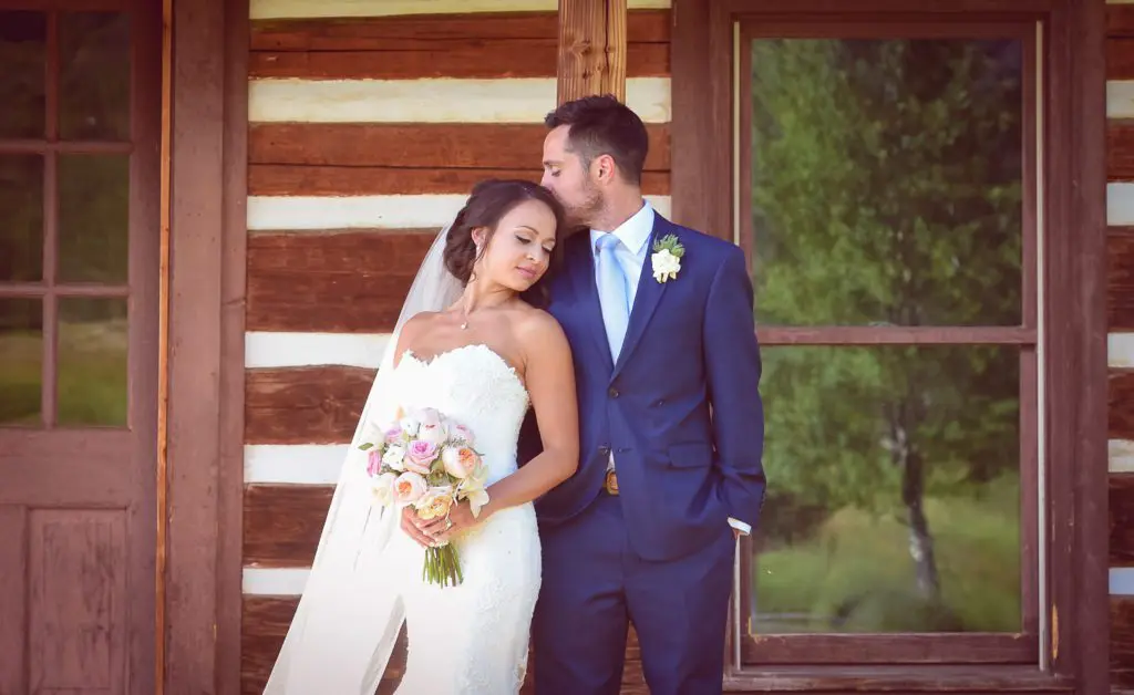 A bride and groom pose for a picture outside.