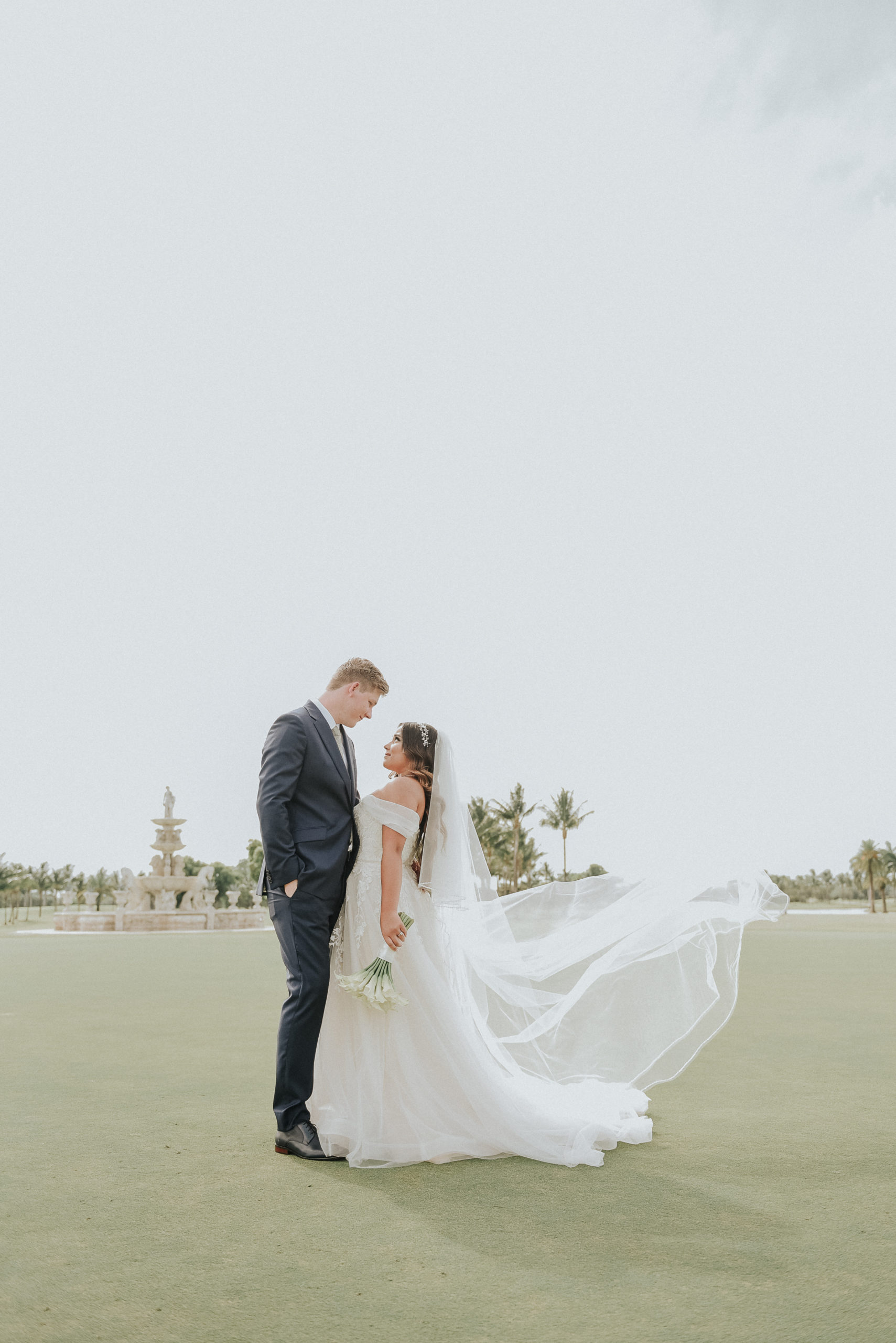 A bride and groom standing in front of the ocean.