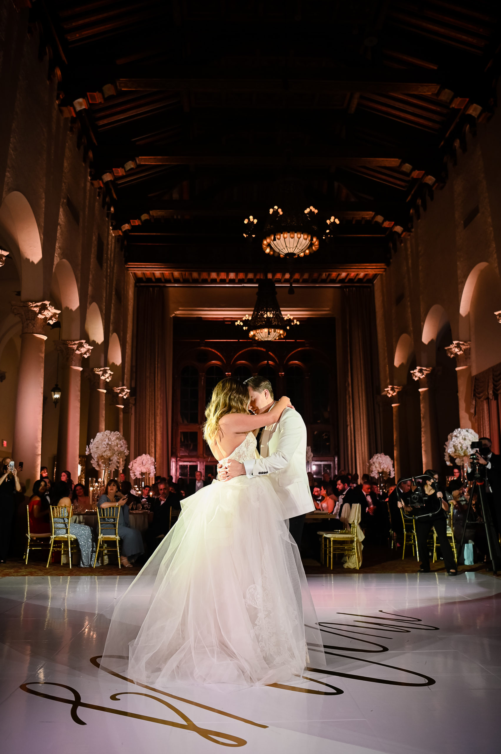 A bride and groom are dancing in front of an audience.