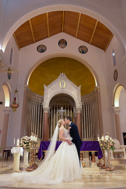A bride and groom kissing in front of the altar.