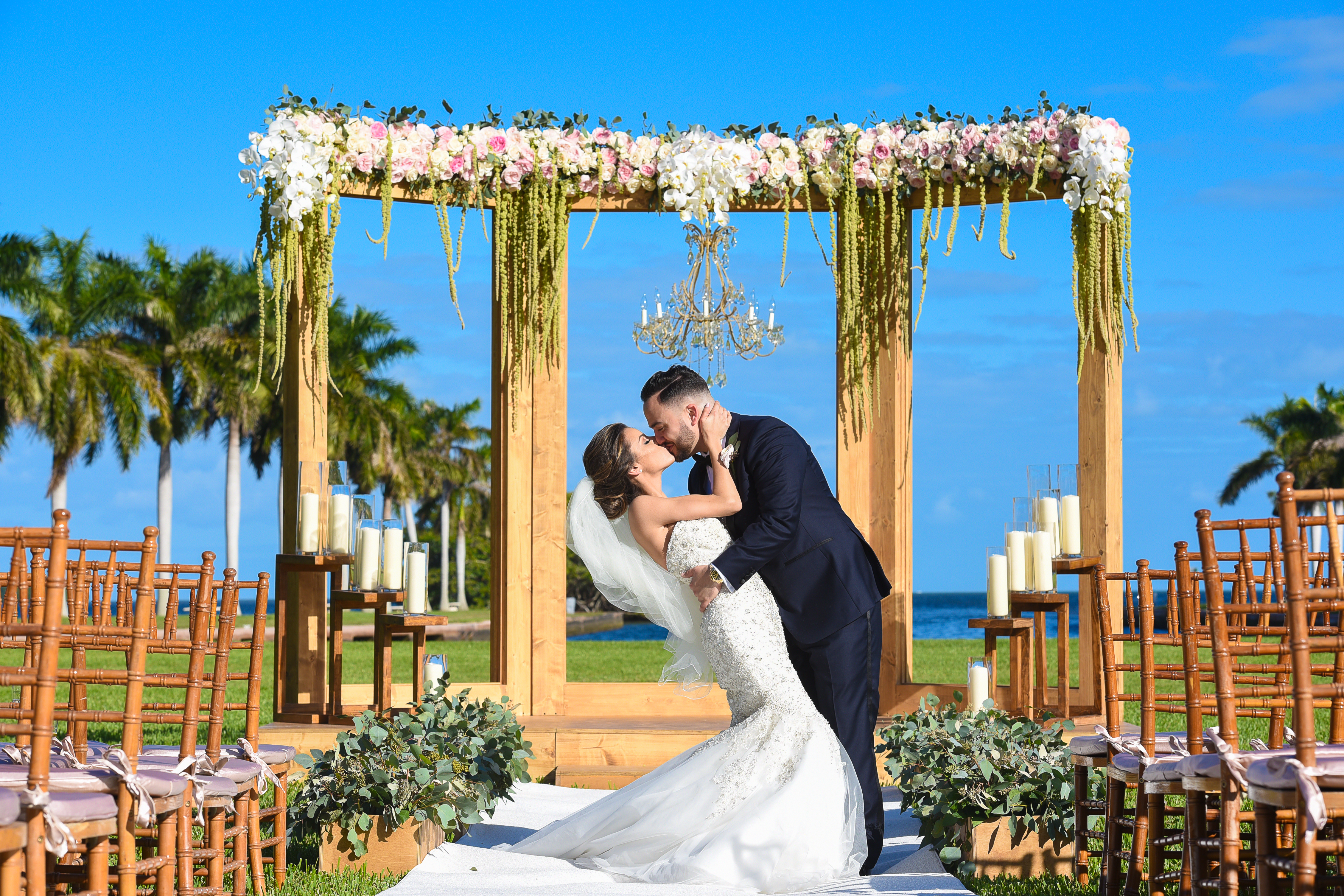 A bride and groom kissing under an arch.