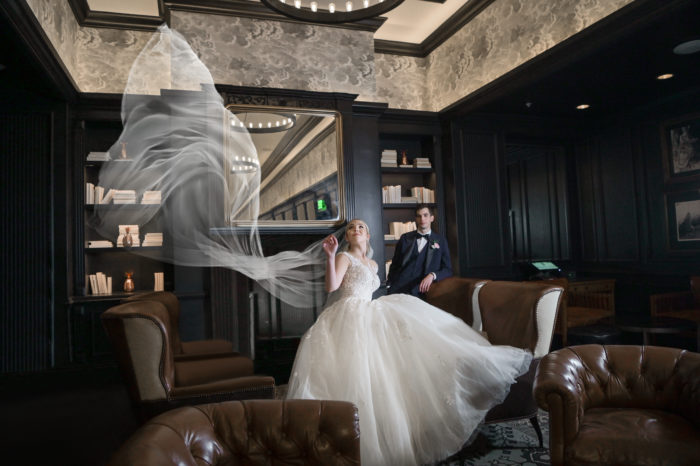 A bride and groom pose for a picture in the lobby of their hotel.
