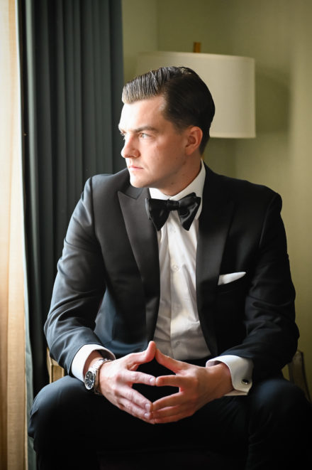 A man in a suit and bow tie sitting down.