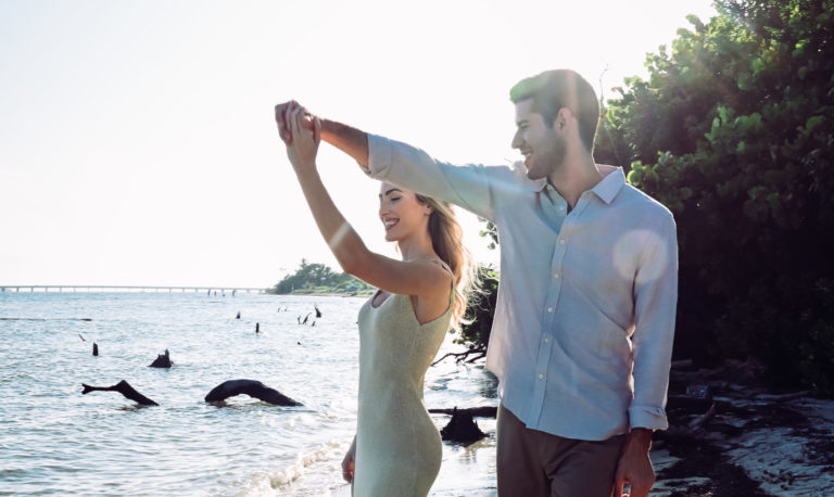 A man and woman are dancing on the beach.