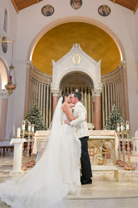 A bride and groom kiss in front of the altar.