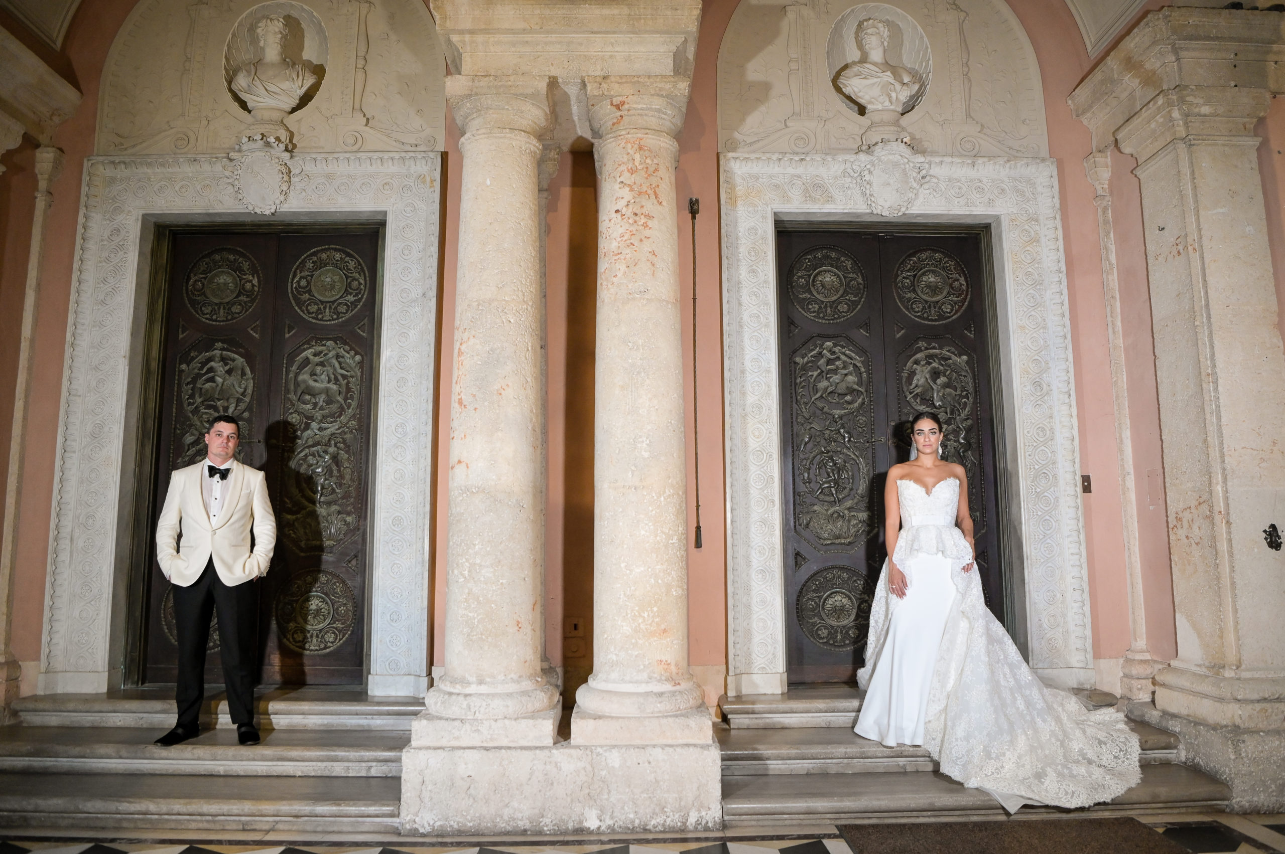 A bride and groom posing for a picture in front of the doors.