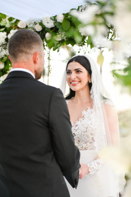 A bride and groom are holding hands in front of the camera.