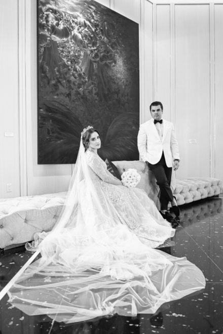 A bride and groom posing for a picture in front of a painting.