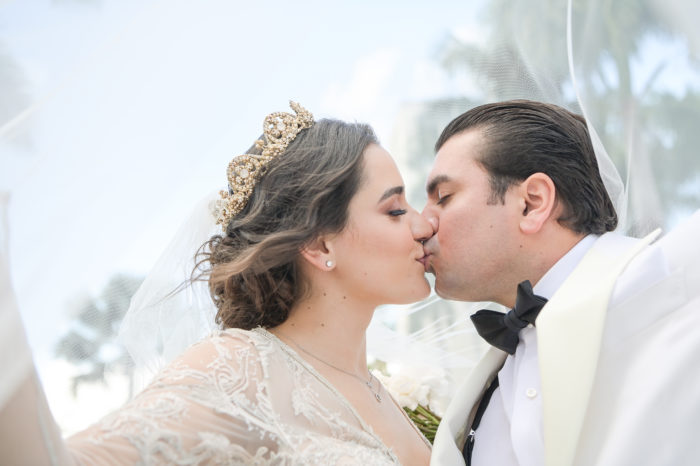 A bride and groom kissing under the veil.