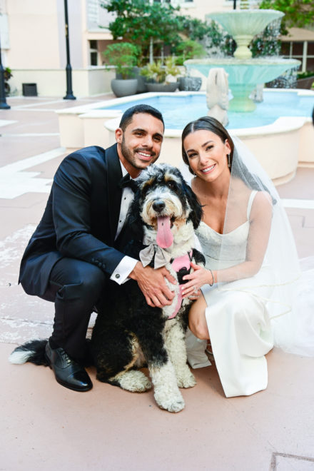 A couple and their dog pose for the camera.