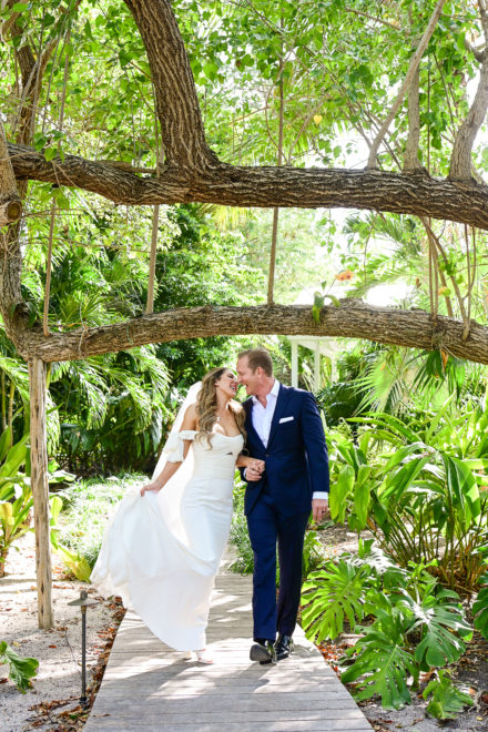 A bride and groom under a tree in the woods