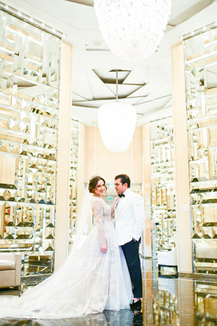 A bride and groom pose for a picture in the hallway of their wedding.