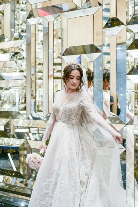 A woman in white dress standing next to a mirror.