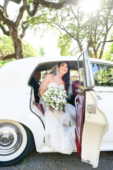 A bride and groom in the back of a car.