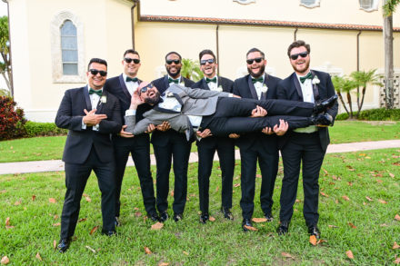 A group of men in suits and bow ties holding each other.