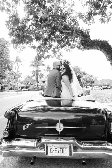 A man and woman kissing in the back of an old car.