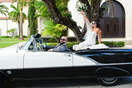 A bride and groom in the back of an old car.