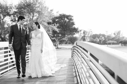 A bride and groom walk across the bridge.