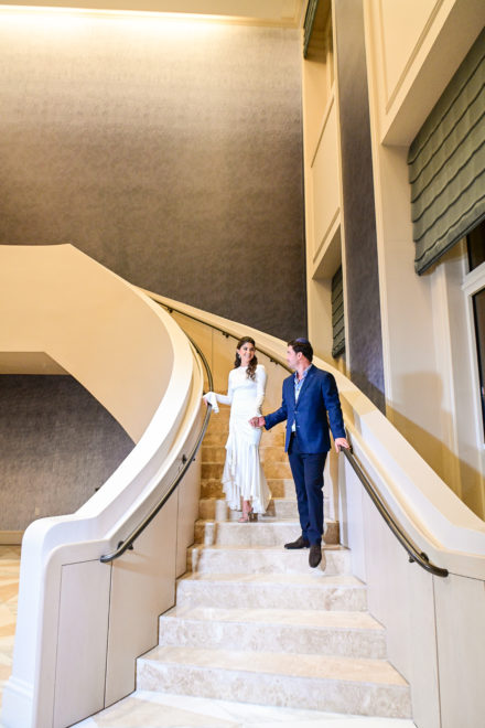 A man and woman standing on the stairs of an indoor building.