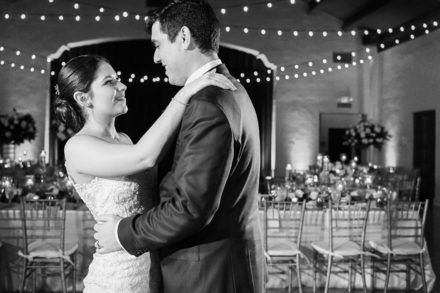 A bride and groom are dancing in front of the lights.