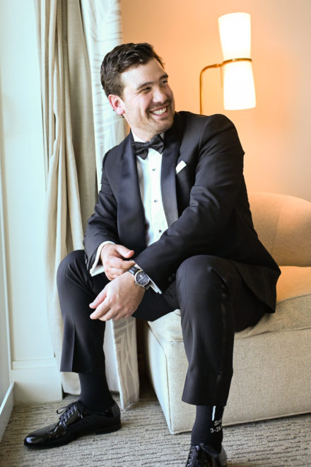 A man in a tuxedo sitting on the couch
