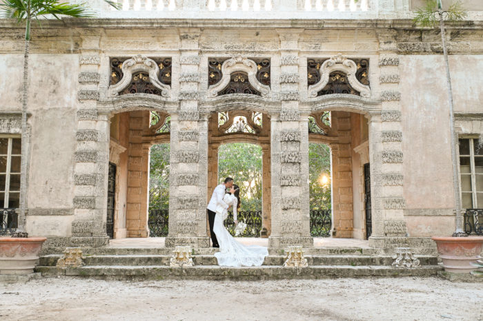 A bride and groom kissing in front of an old building.