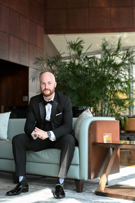 A man in a tuxedo sitting on top of a couch.