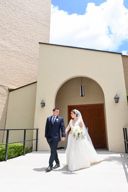 A bride and groom walking outside of the church.