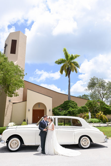 A couple is standing in front of a white car.