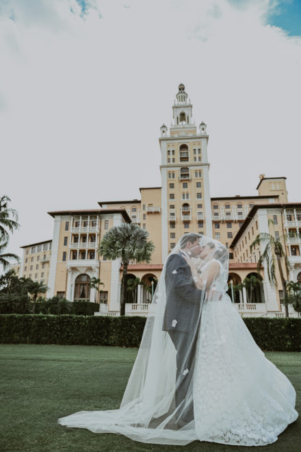 A bride and groom kissing in front of the biltmore hotel.