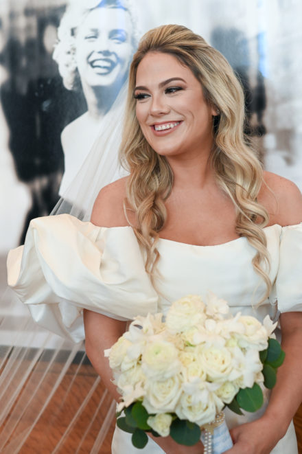 A beautiful blonde bride holding her bouquet.