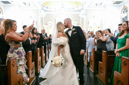 A bride and groom kissing in front of the crowd.