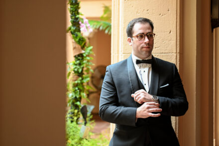 A man in a tuxedo standing next to a wall.
