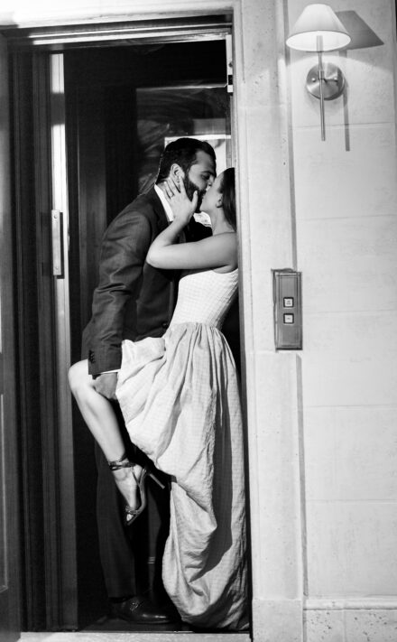 A man and woman kissing in front of a door.