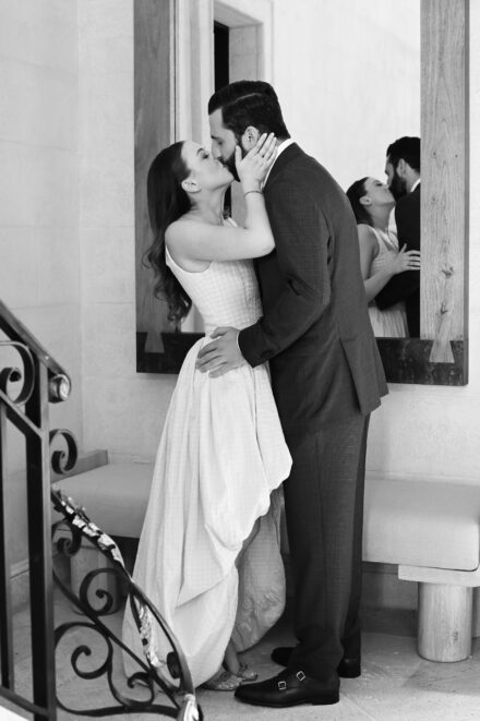 A man and woman kissing in front of a mirror.