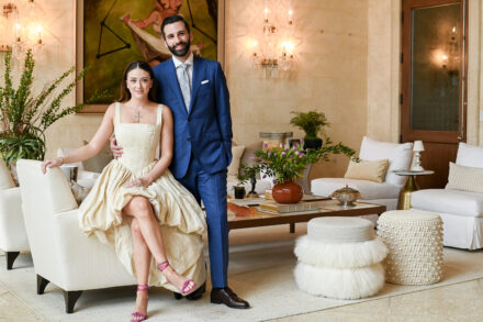 A man and woman posing for the camera in front of a couch.