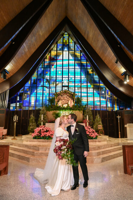 A bride and groom kissing in front of the altar.
