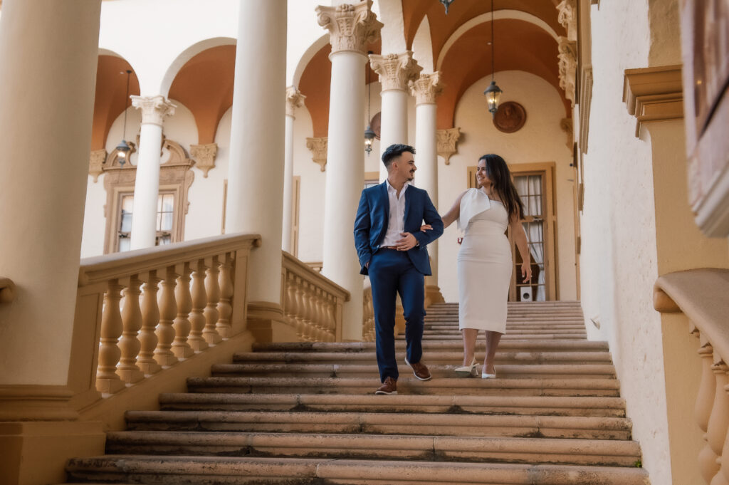 A man and woman walking up the stairs of an old building.
