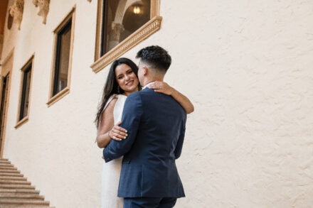 A man and woman embracing in front of a building.