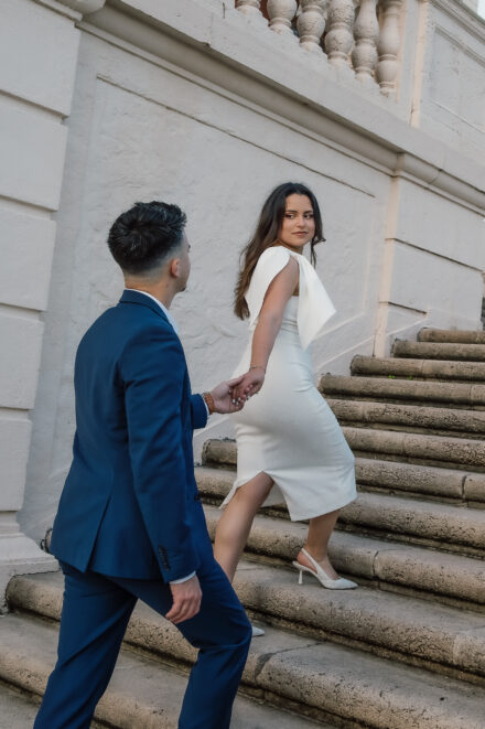 A man and woman walking up steps holding hands.
