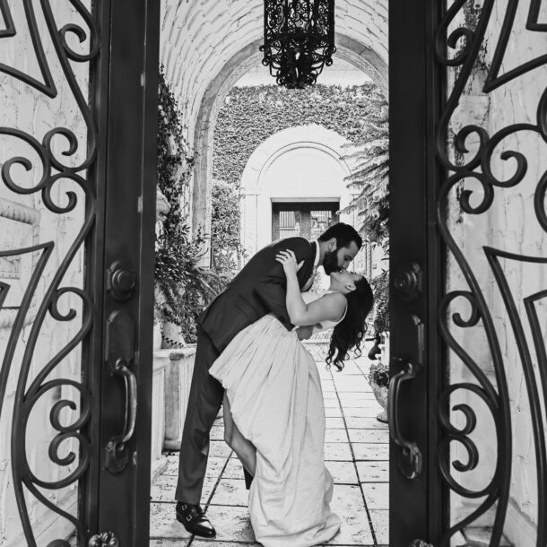 A man and woman kissing in front of an ornate door.