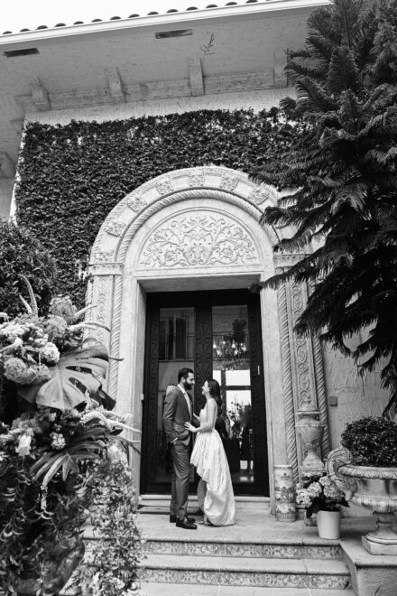 A black and white photo of two people standing in front of a building.