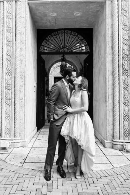 A man and woman kissing in front of an archway.