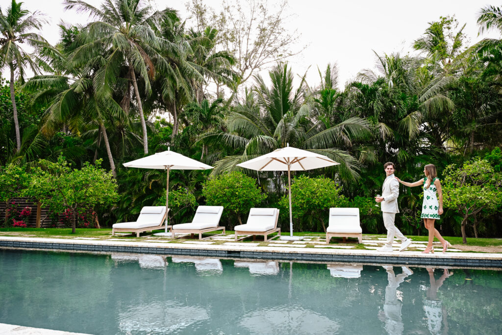 Couple by tropical pool with lounge chairs.